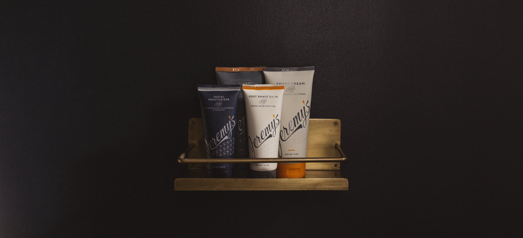 Jeremy's shave and skin products on a brass bathroom shelf
